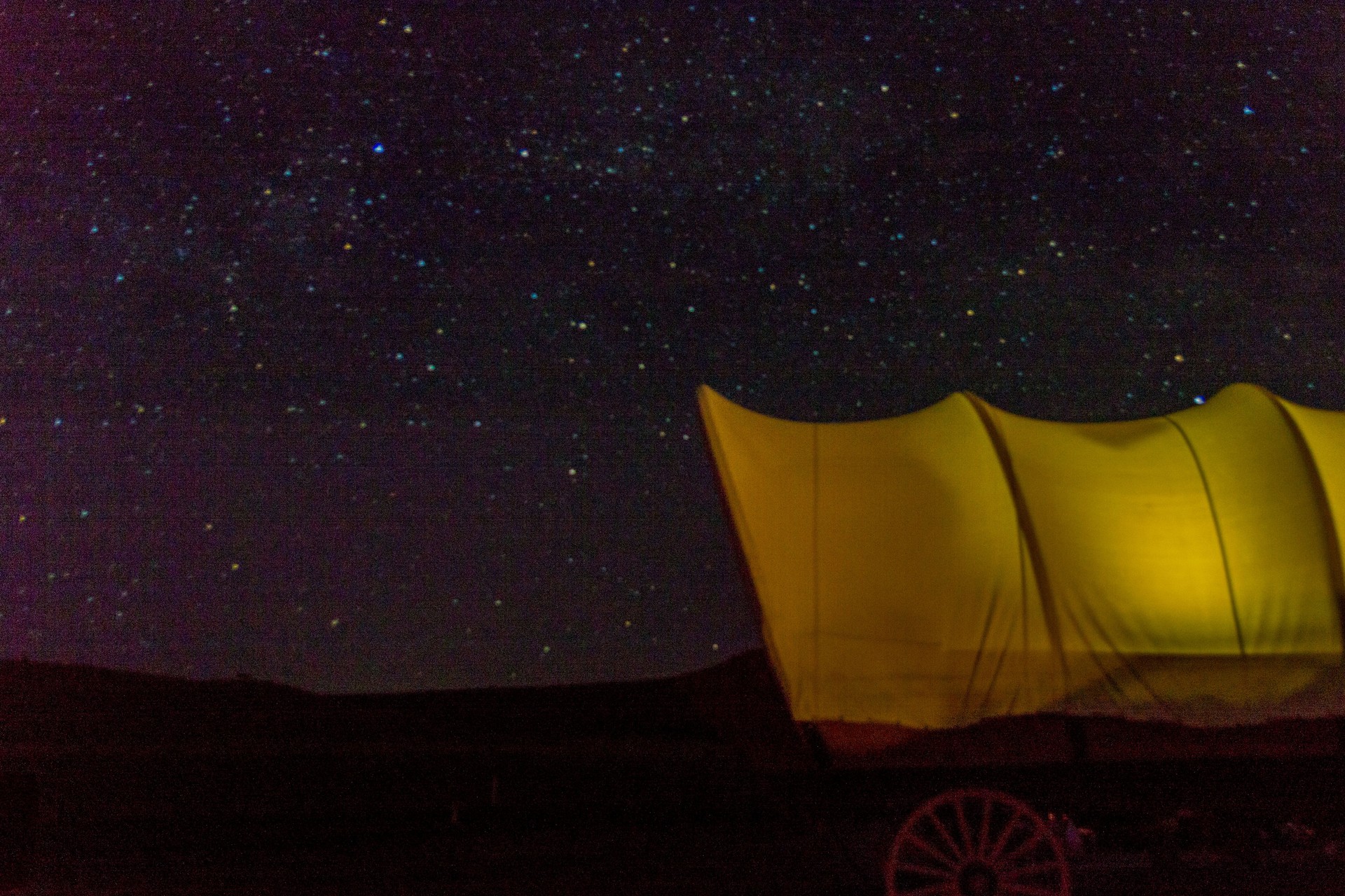Glamping Camping Wagon Set up at a Mountain Lake and Glowing under the Night Sky and Stars Glamping Camping Wagon Set up at a Mountain Lake and Glowing under the Night Sky and Stars